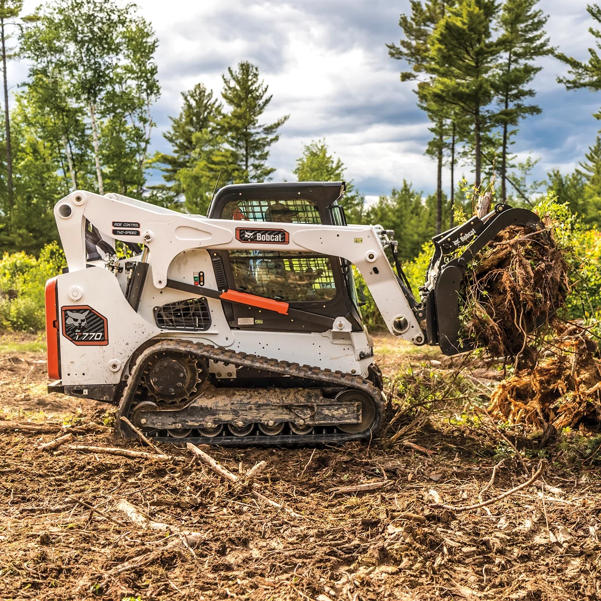 Bobcat T770 compact track loader lifting an uprooted tree during storm cleanup